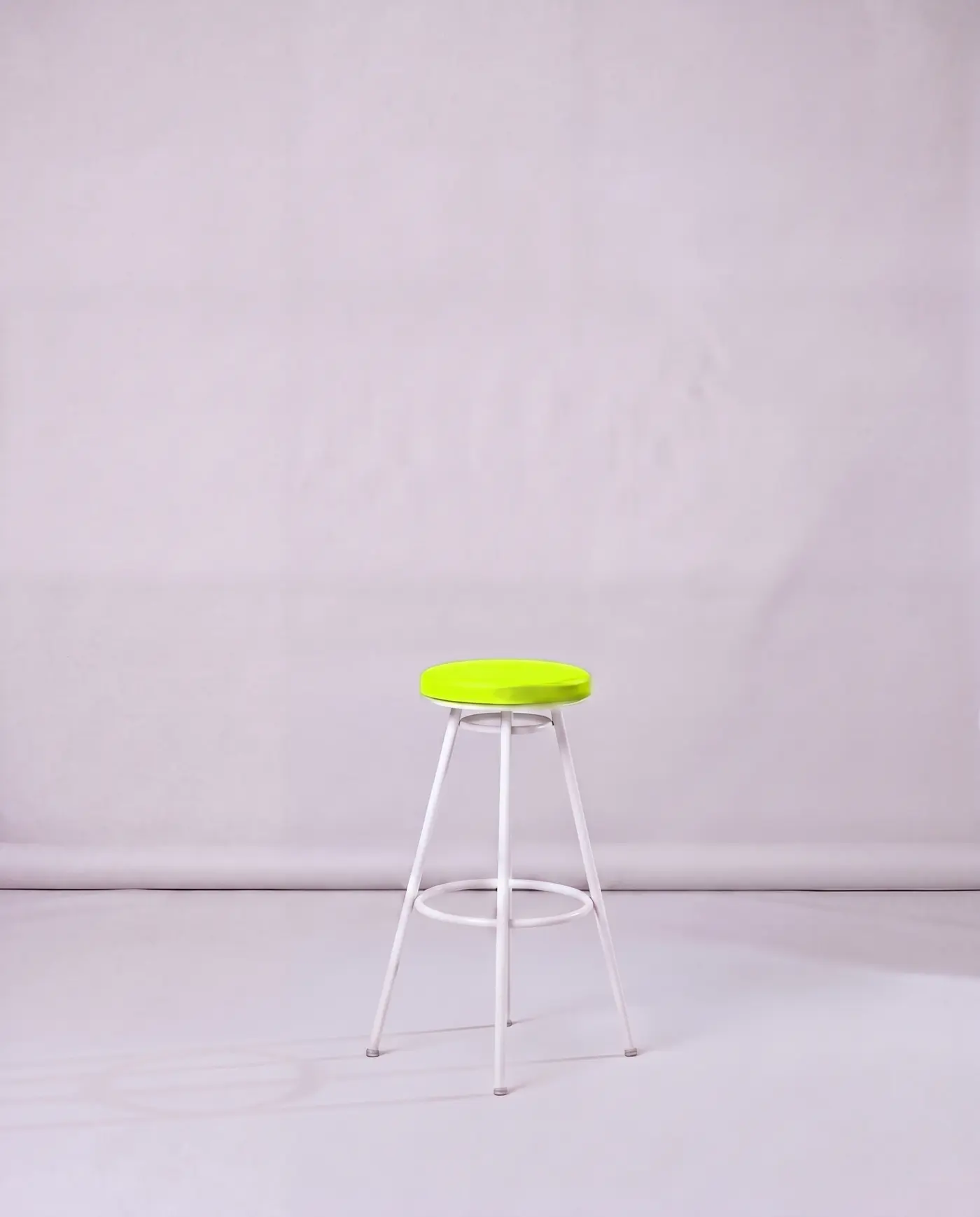 An empty lime stool in Socialize's white studio in Lusail, Doha, waiting for its next team member